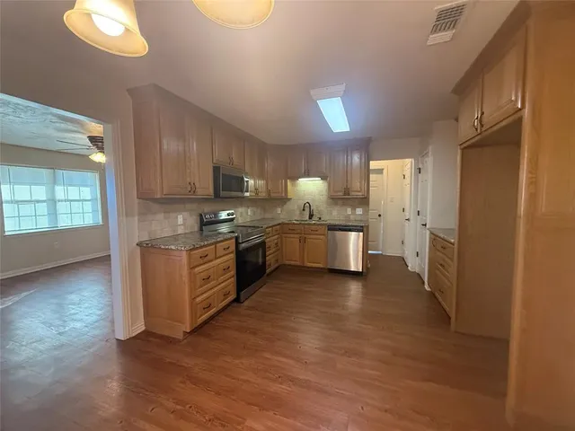 a large kitchen with stainless steel appliances granite countertop a stove a sink dishwasher and a refrigerator