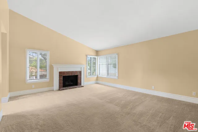 an empty room with a fireplace and windows