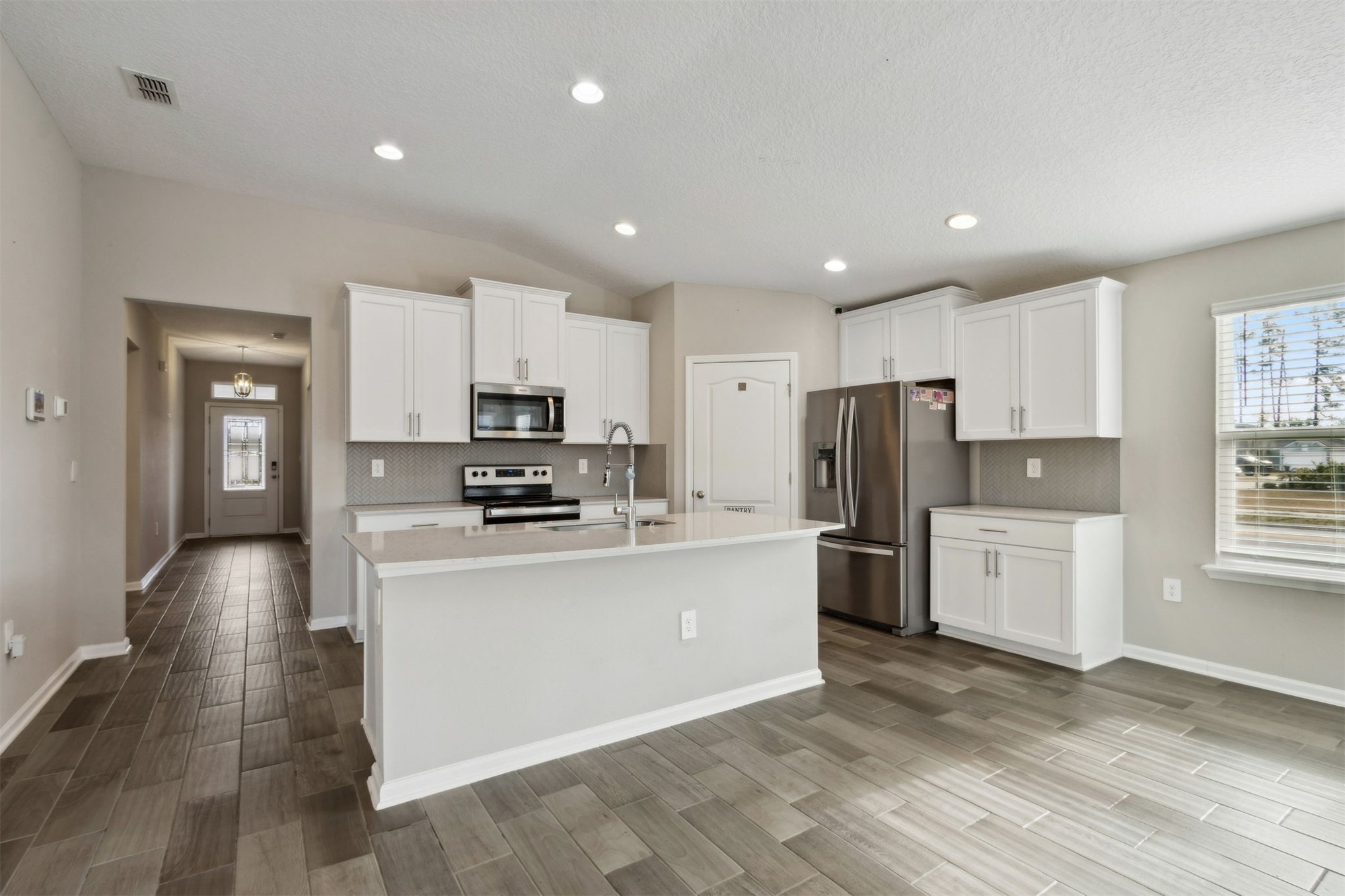 65860 Edgewater Drive Yulee, FL 32097 - Photo 3 of 39 a kitchen with white cabinets and stainless steel appliances