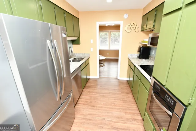 a kitchen with stainless steel appliances a refrigerator and a wooden floor