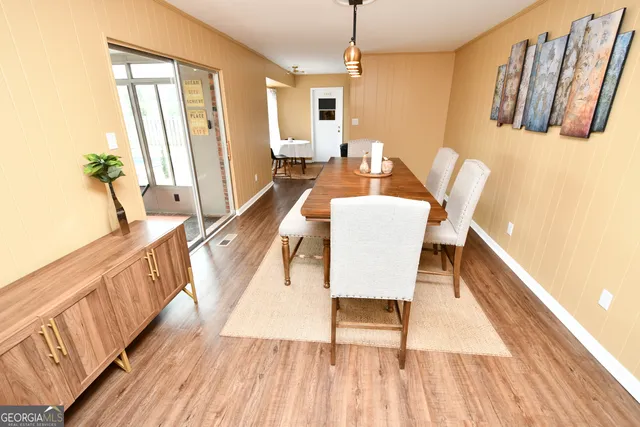 a dining room with wooden floor and large windows