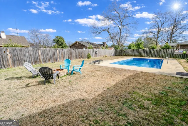 a view of backyard with swimming pool and furniture