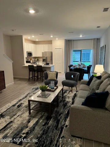 a living room with furniture and a dining table with wooden floor