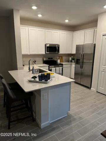 a kitchen with stainless steel appliances a sink a stove a microwave a refrigerator a center island and cabinets