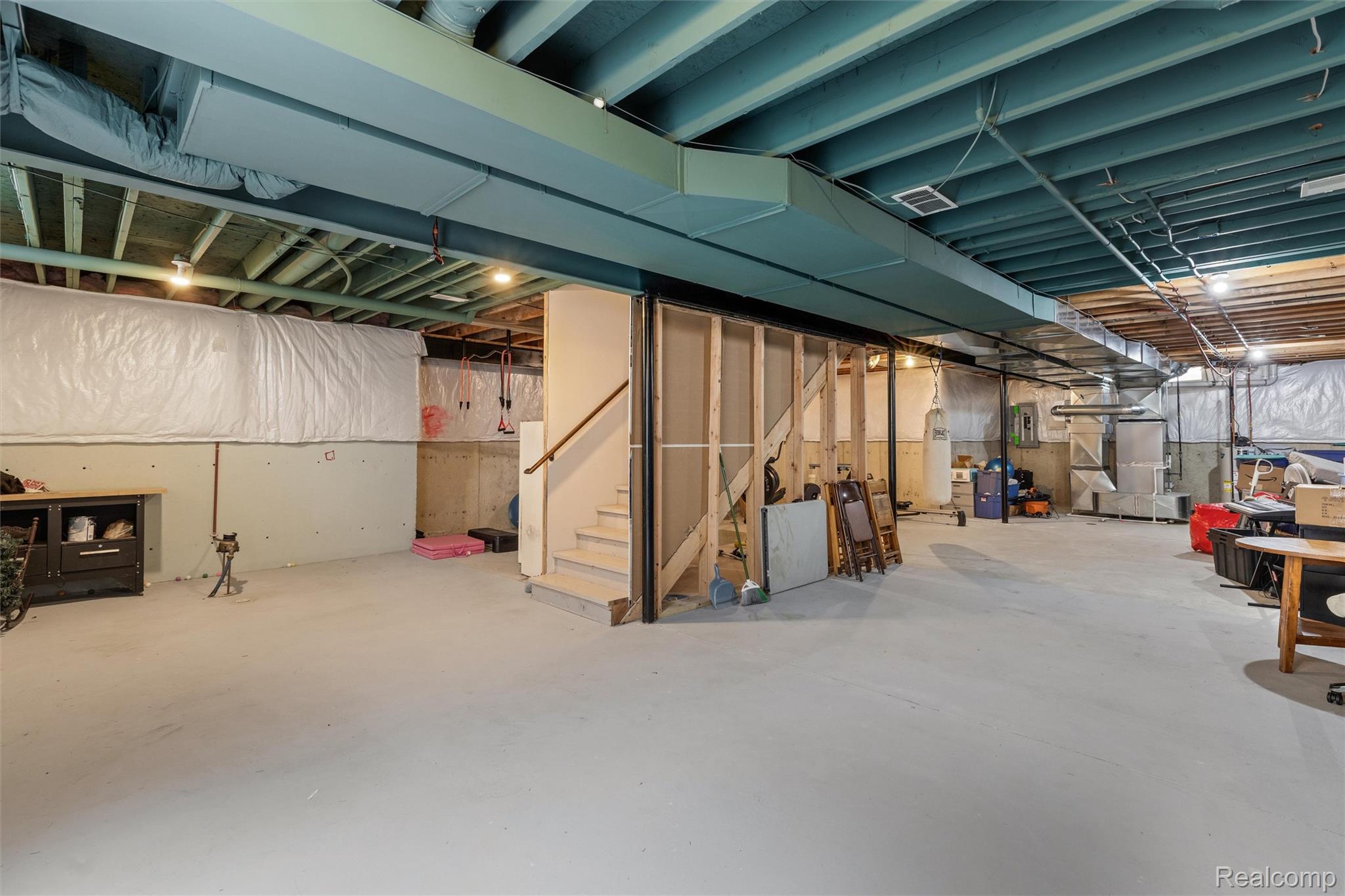1016 West Snell Road Rochester, MI 48306 - Photo 31 of 35 Unfinished basement space featuring exposed ceiling joists, concrete flooring, and partial wall framing, offering expansive potential