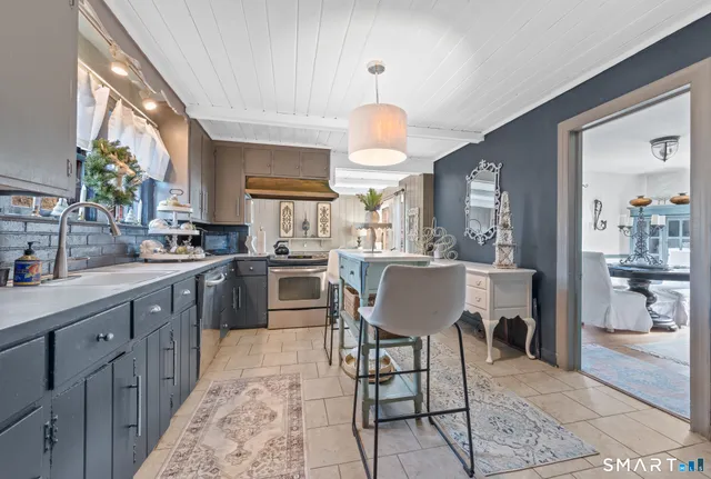 a kitchen with stainless steel appliances a table chairs sink and cabinets