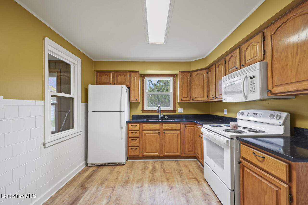 227 Protection Avenue North Adams, MA 01247 - Photo 11 of 25 a kitchen with a refrigerator a stove a sink dishwasher and wooden cabinets with wooden floor