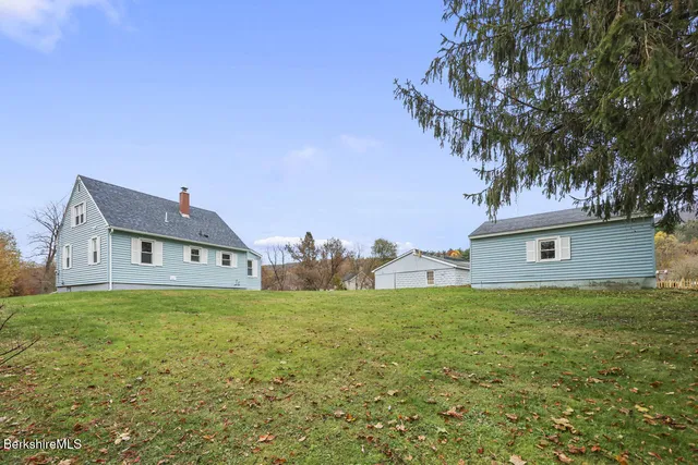a house that is sitting in the grass with large trees