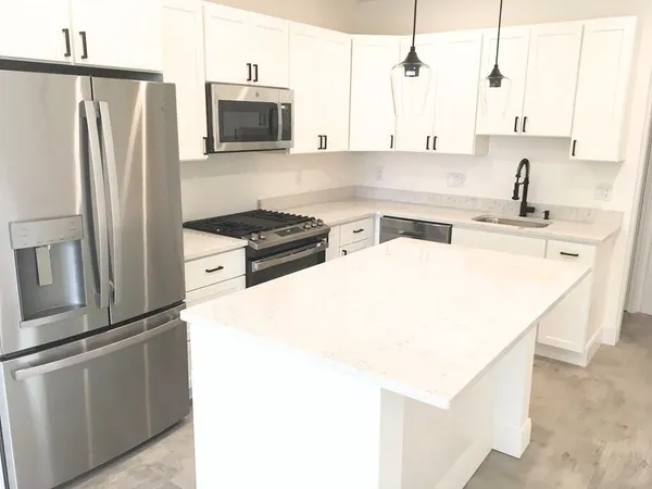 a kitchen with stainless steel appliances a refrigerator a stove a sink and white cabinets