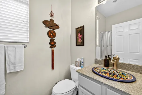 a bathroom with a granite countertop sink a toilet and a mirror