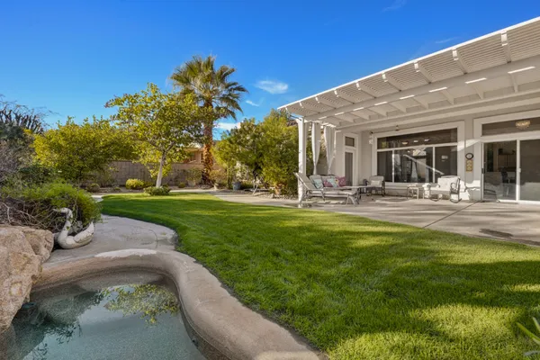 a view of a patio with table and chairs potted plants and palm tree