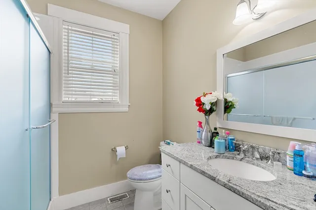 a bathroom with a granite countertop sink toilet and a mirror