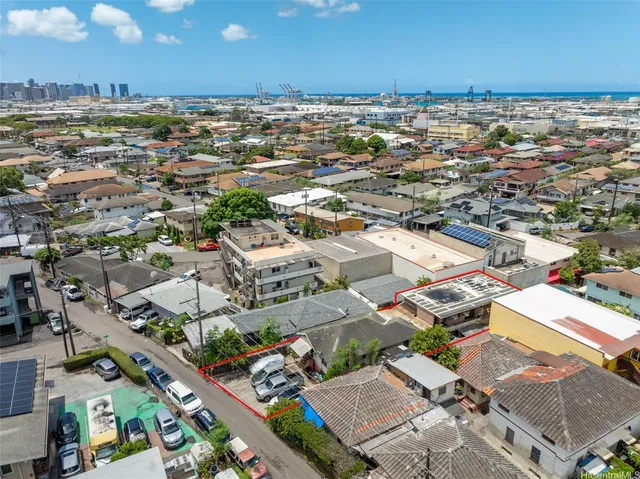 an aerial view of a city with lots of residential buildings and ocean view in back