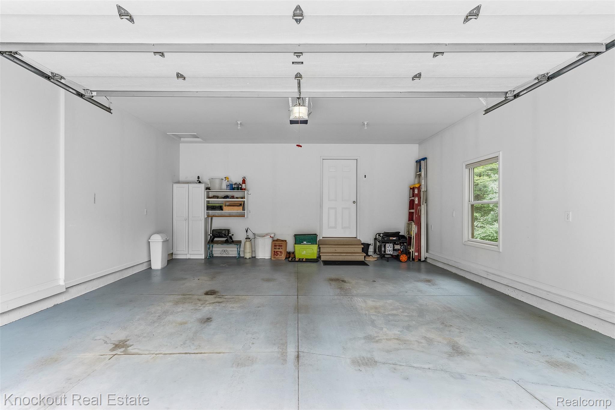 8436 Birch Run Road Millington, MI 48746 - Photo 33 of 44 Spacious garage featuring a concrete floor, bright white walls, and an overhead garage door mechanism