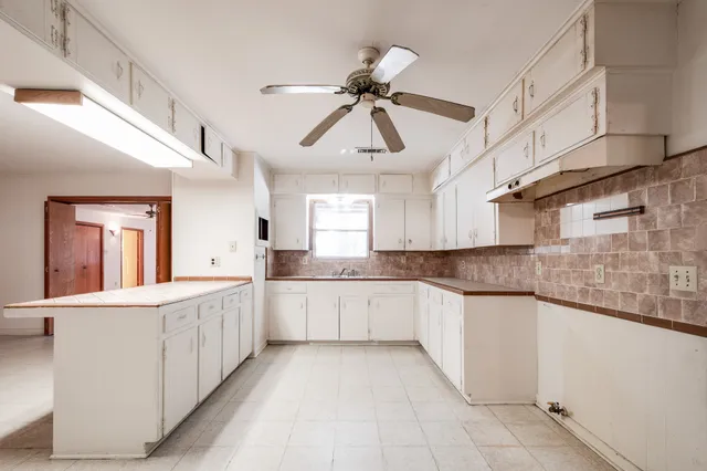 a kitchen with white cabinets a sink dishwasher and a stove with wooden floor