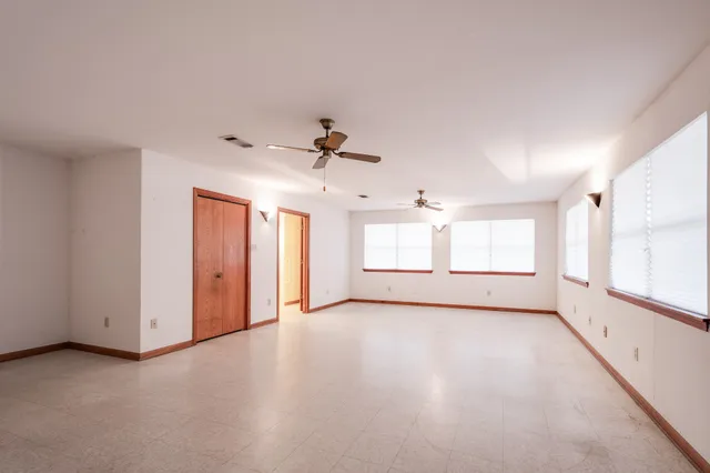 an empty room with windows and cabinet