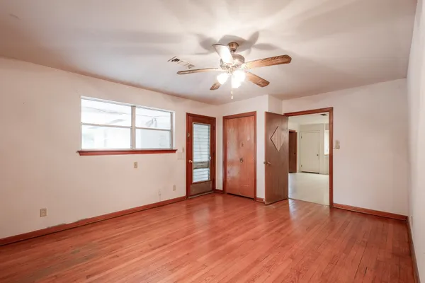 a view of an empty room with window and wooden floor