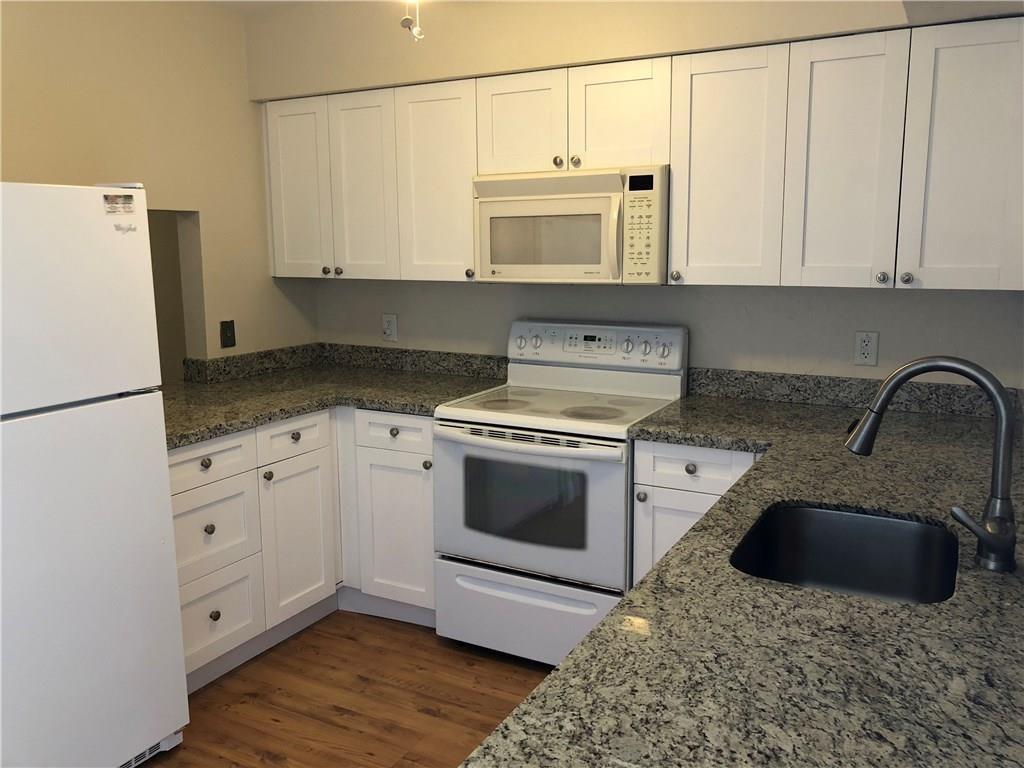 3850 Northeast 21st Way, Unit 62 Lighthouse Point, FL 33064 - Photo 4 of 13 a kitchen with granite countertop white cabinets and white appliances