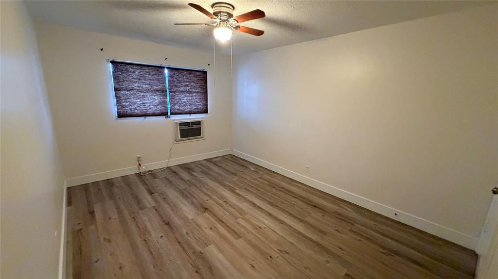 3850 Northeast 21st Way, Unit 62 Lighthouse Point, FL 33064 - Photo 7 of 13 an empty room with wooden floor chandelier fan and windows