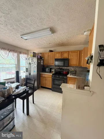 a kitchen with stainless steel appliances kitchen island granite countertop a stove top oven a sink a dining table and chairs