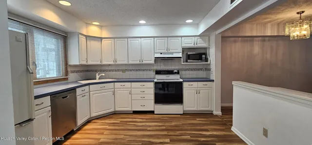 a view of a kitchen with kitchen island a window wooden floor and a refrigerator