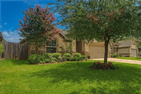 a front view of a house with a yard and large tree