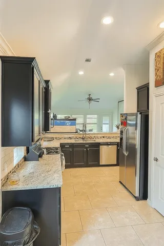 a kitchen with stainless steel appliances granite countertop a sink and a refrigerator
