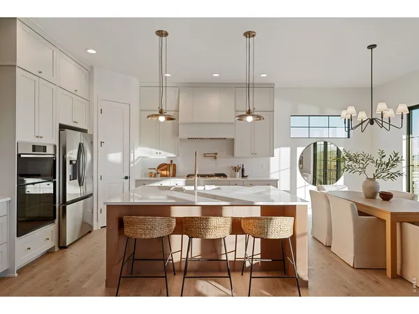 a open kitchen with kitchen island a stove a refrigerator a sink dishwasher a dining table and chairs with wooden floor