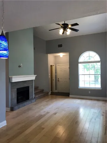 a view of an empty room with wooden floor fireplace and a window