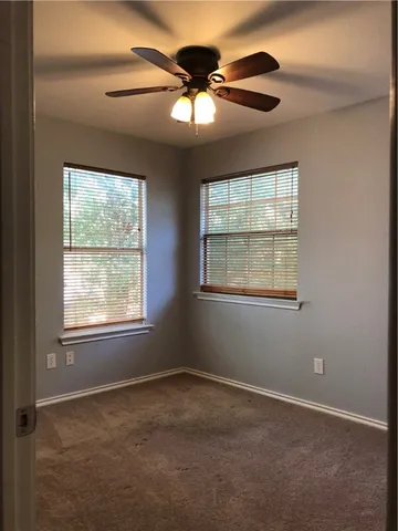 an empty room with a chandelier fan and windows