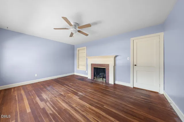 a view of empty room with wooden floor and fireplace