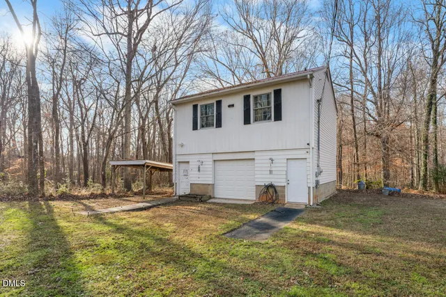 a view of a white house with a yard and large trees
