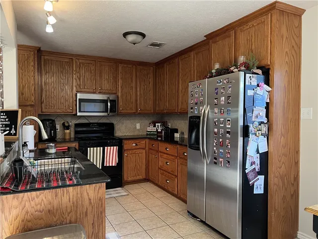 a kitchen with stainless steel appliances granite countertop a refrigerator and a stove top oven