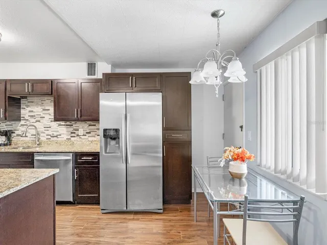 a kitchen with stainless steel appliances granite countertop a sink refrigerator and cabinets