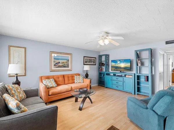 a living room with furniture kitchen view and a wooden floor