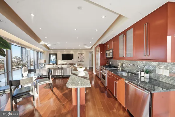 a large kitchen with stainless steel appliances granite countertop a lot of counter space and a wooden floor