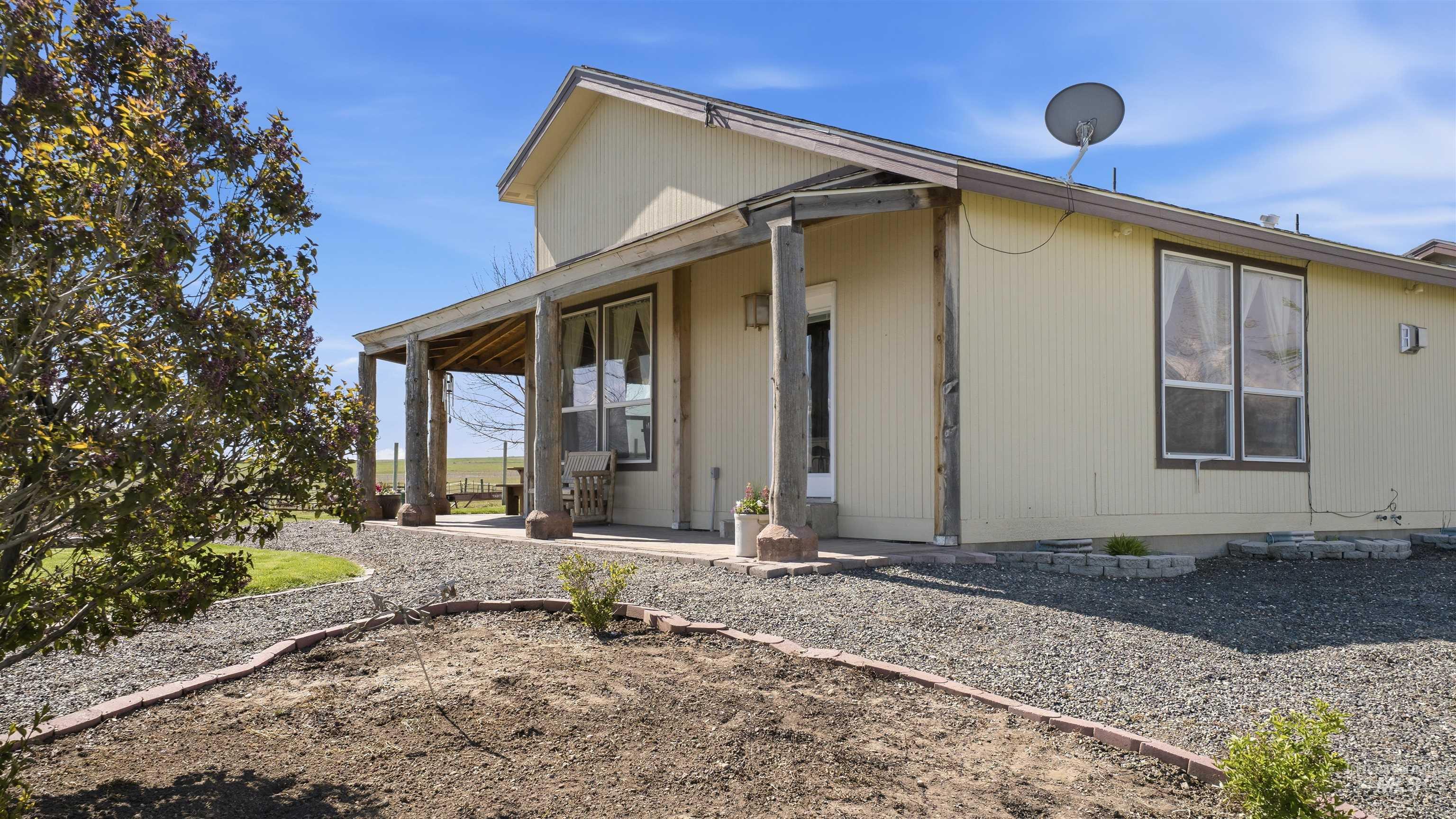 19397 Cloverland Road Asotin, WA 99402 - Photo 5 of 37 Exterior property showcasing a covered porch with rustic wood columns, light-toned siding, and multiple windows