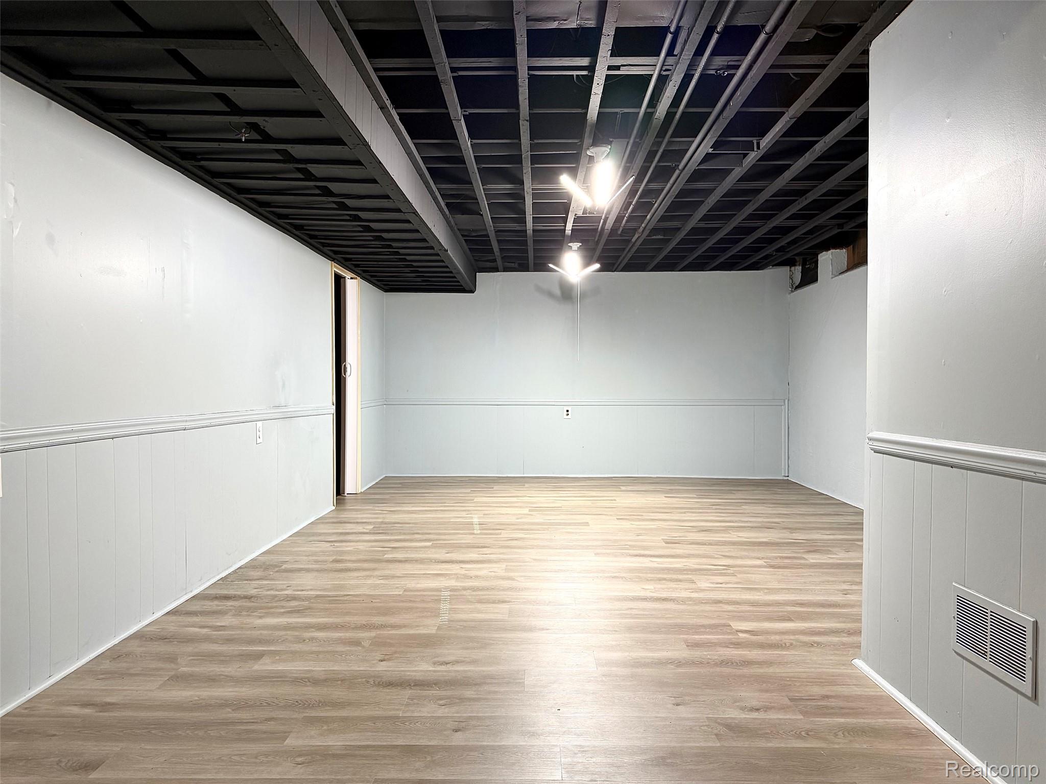 2852 Trailwood Drive Rochester, MI 48309 - Photo 23 of 28 Wood-finish flooring, white paneling, exposed black ceiling joists, and recessed lighting