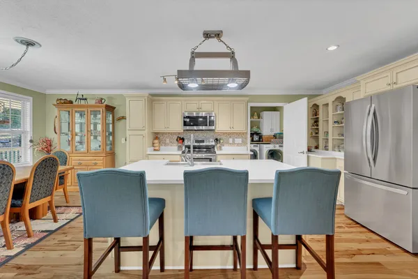 a kitchen with stainless steel appliances granite countertop a dining table chairs refrigerator and cabinets