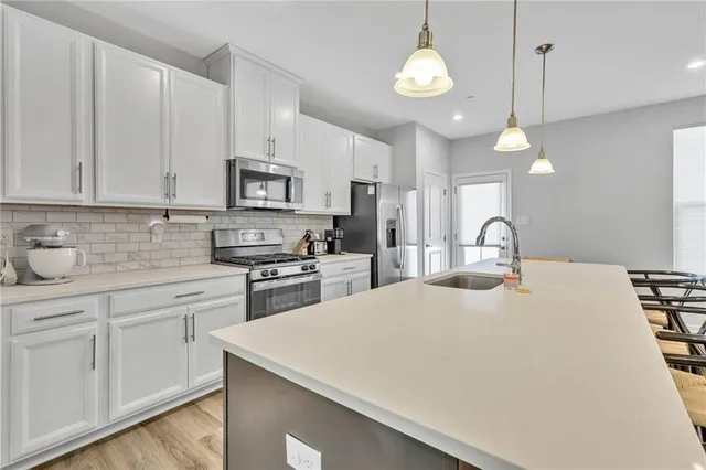 a kitchen with stainless steel appliances granite countertop a sink a stove a refrigerator cabinets and chairs