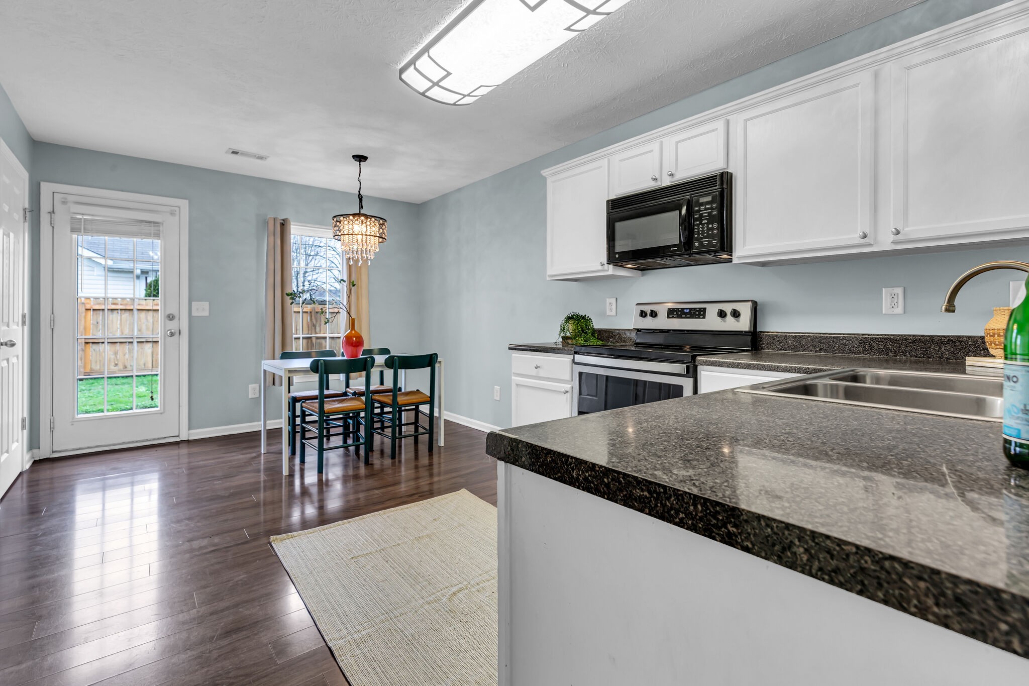 4026 Deer Run Trace Spring Hill, TN 37174 - Photo 11 of 29 a kitchen with stainless steel appliances granite countertop a stove top oven a sink a dining table and chairs with wooden floor