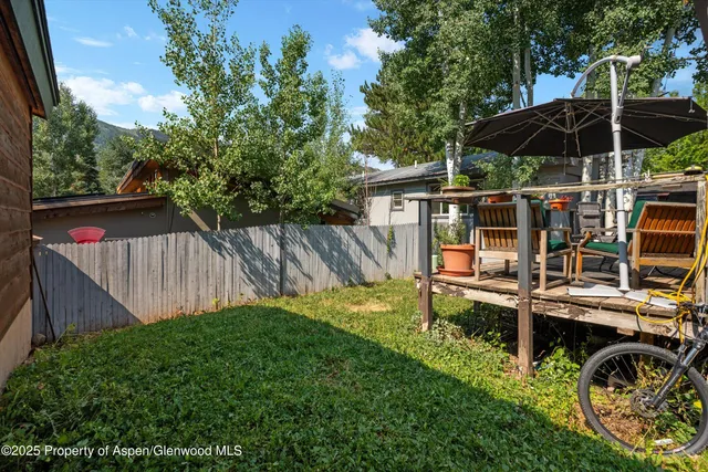 a view of a chair and table in backyard of the house