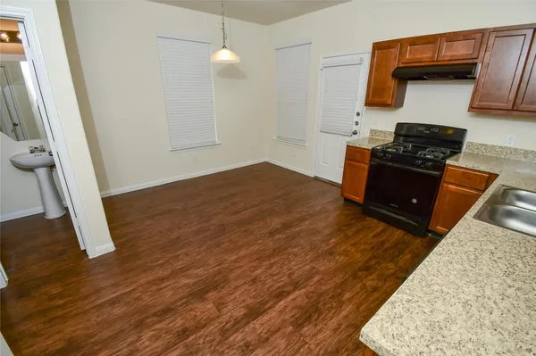 a kitchen with wooden floor and electronic appliances
