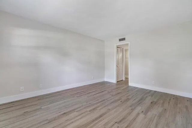 a view of an empty room with wooden floor and a window