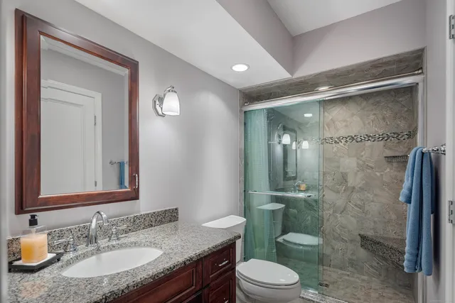 a bathroom with a granite countertop sink toilet a mirror and shower