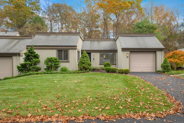 front view of house with a yard and trees all around