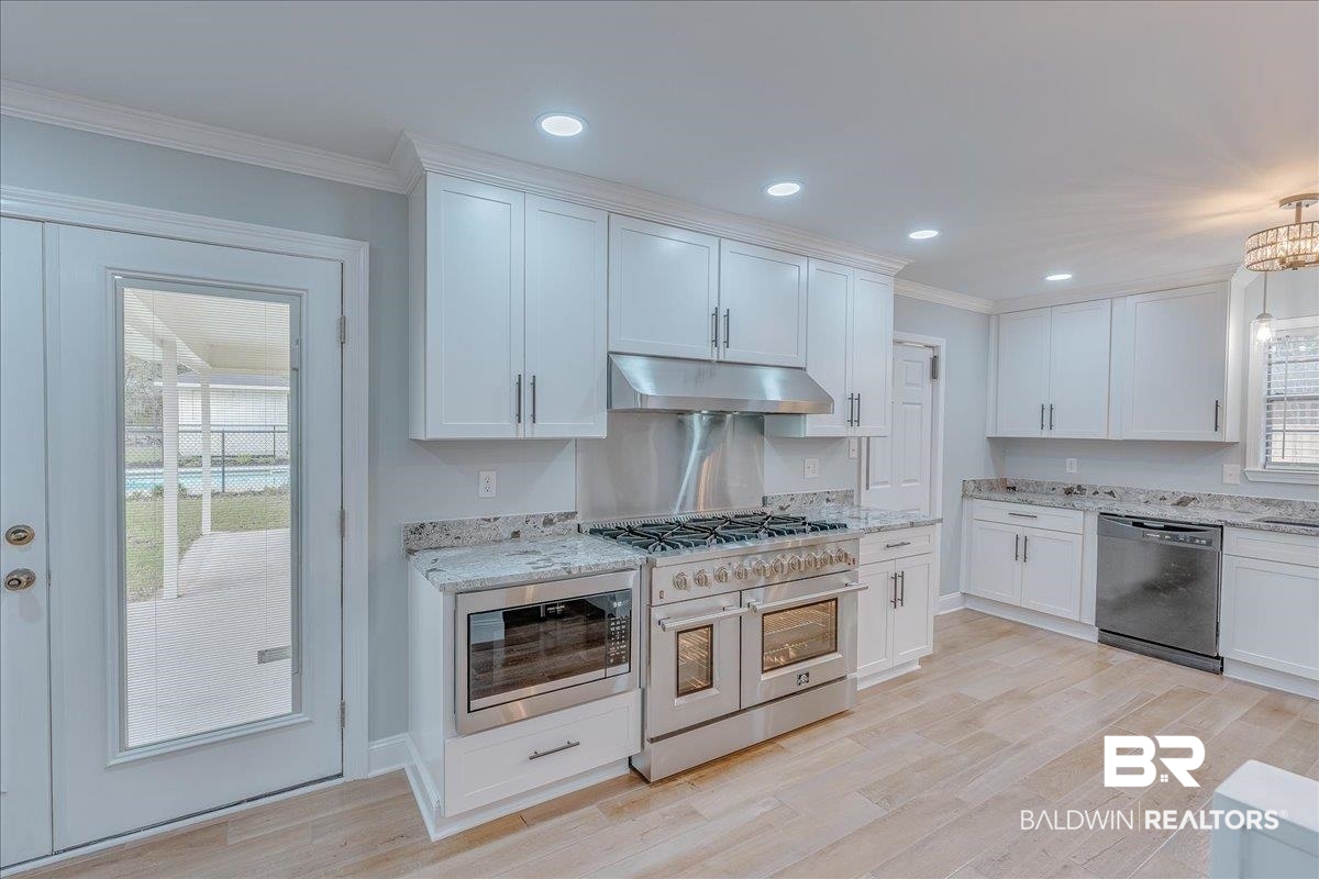 440 Dykes Road Mobile, AL 36608 - Photo 14 of 49 Kitchen featuring crown molding, under cabinet range hood, light wood-style flooring, white cabinets, and stainless steel appliances
