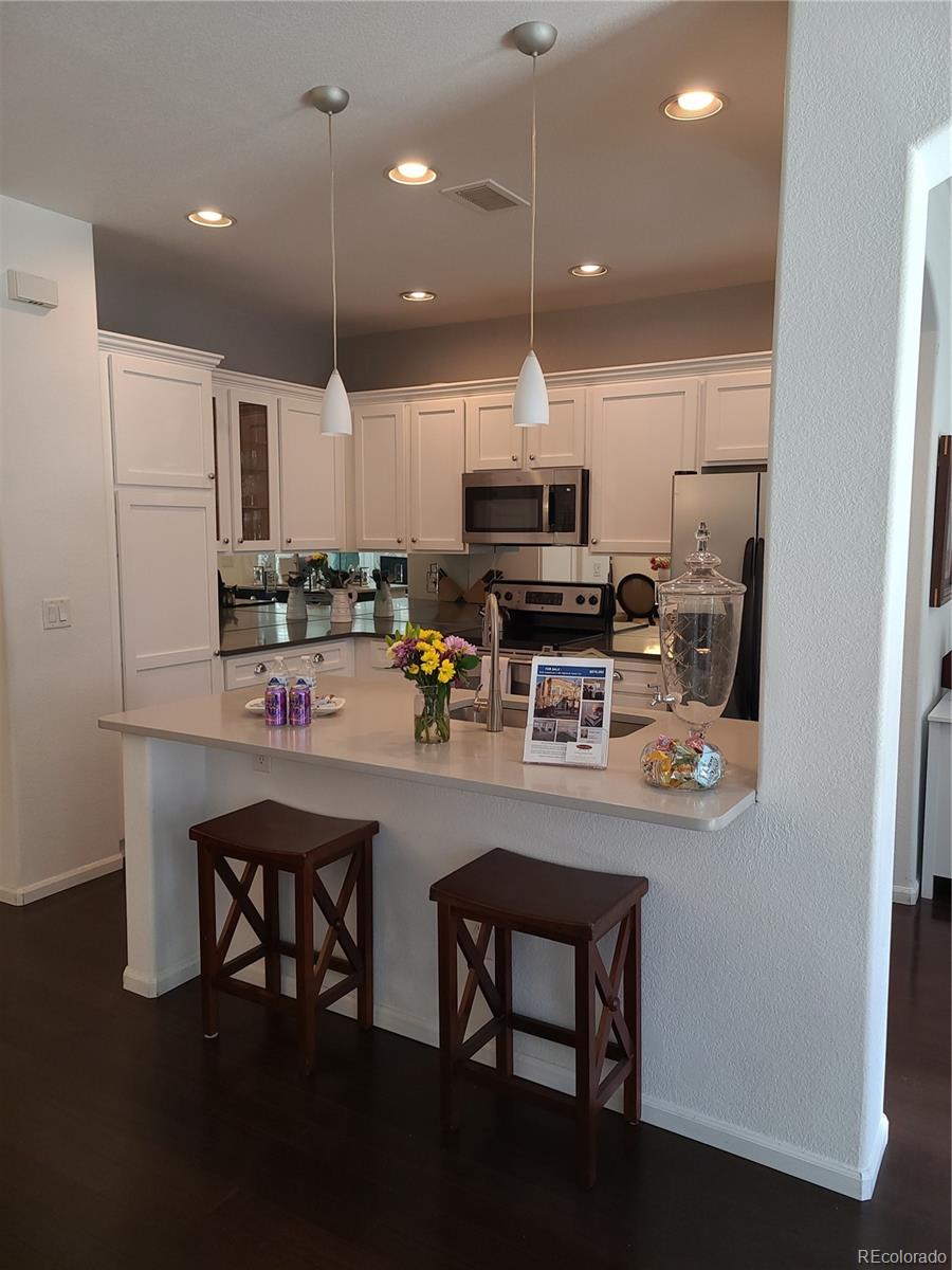 9492 Cedarhurst Lane, Unit B Highlands Ranch, CO 80129 - Photo 4 of 17 a kitchen with stainless steel appliances a dining table chairs refrigerator and microwave