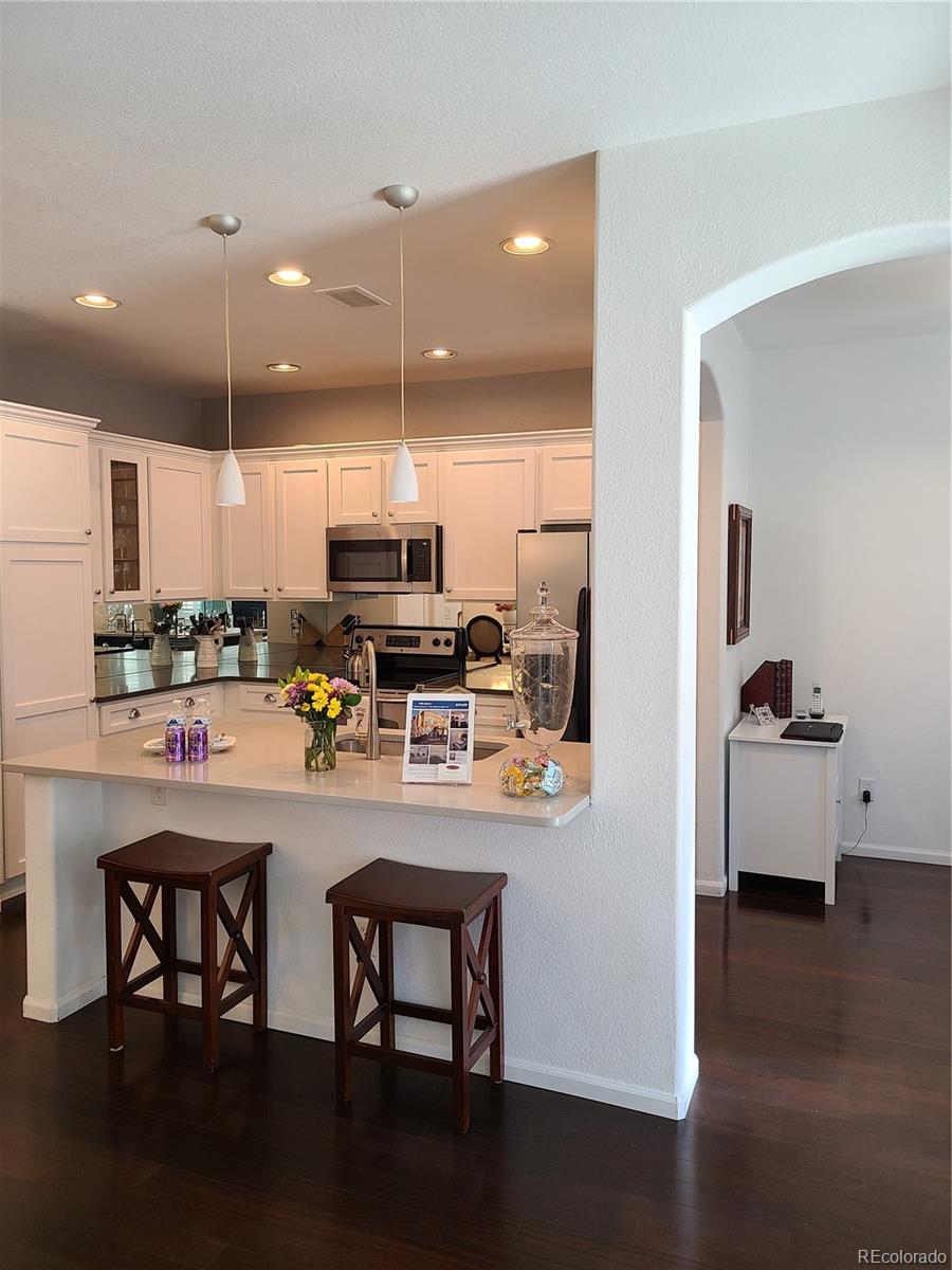 9492 Cedarhurst Lane, Unit B Highlands Ranch, CO 80129 - Photo 6 of 17 a kitchen with stainless steel appliances a dining table chairs refrigerator and sink