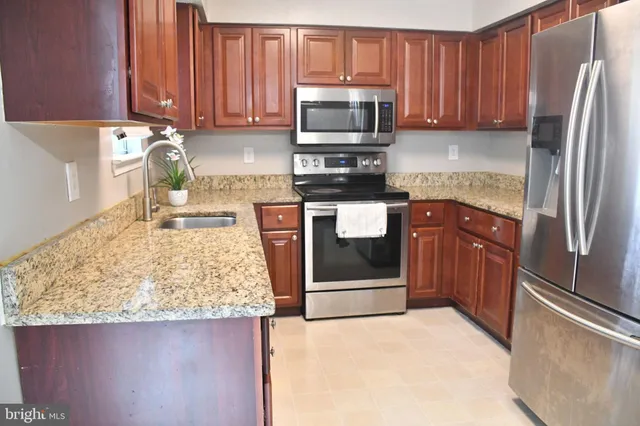 a kitchen with granite countertop wooden cabinets and white appliances